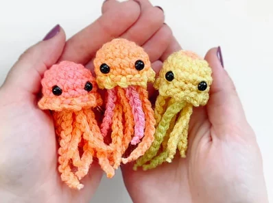 3 amigurumis en forme de poulpe réalisés au crochet à la main : rose, orange et jaune