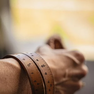 Bracelet mètre en cuir enroulable marron porté sur un bras
