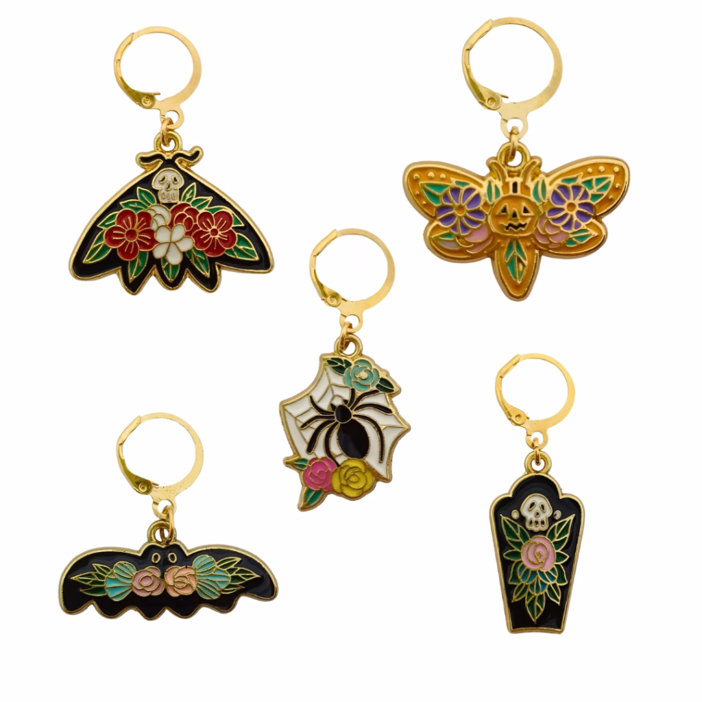 Apporte couleur et symbolique à tes ouvrages avec les Marqueurs de maille Día de los Muertos : araignée fleurie, cercueil, chauve-souris, citrouille et papillon mystique.